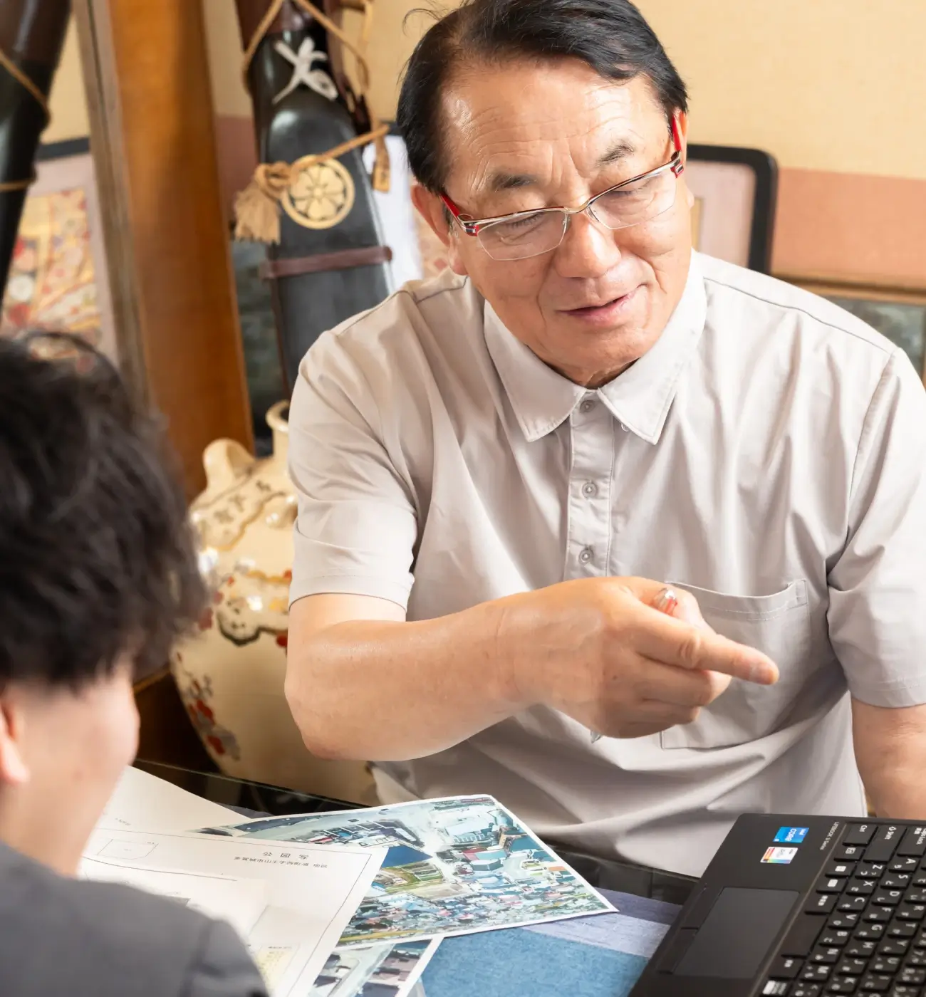 資料とノートパソコンを広げて、打ち合わせをしている様子の画像